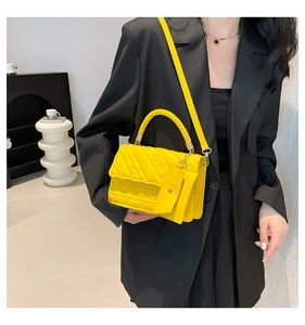 Detail of yellow crossbody bag with FASHION embossing and woven handle on model