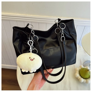 Détail du grand sac cabas noir montrant la texture cuir PU, chaîne argentée et pompon