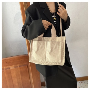 Detail of off-white corduroy tote bag showing front pockets and minimalist texture