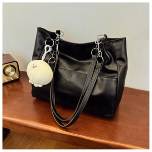 Detail of black tote bag with metal chain strap and cute white octopus plush charm