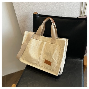 Detail view of cream corduroy tote bag featuring two large front pockets and FASHION leather tag