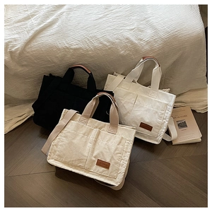 Detailed view of large corduroy tote bags in black, white, and beige with leather accents