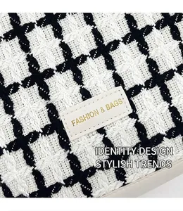 Detail of woven black and white texture with leather Fashion & Bags logo patch on tote
