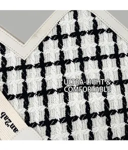 Macro detail of black and white checkered tweed fabric with durable beige strap