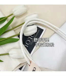 Detailed shot of white rope handles with fine stitching and woven brand tag on tote bag