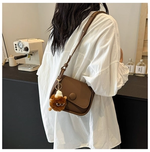 Close-up of a brown vintage saddle bag with adjustable strap and plush charm detail