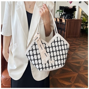Detail of checkered tote bag with V-shaped cut and scarf-wrapped white handles