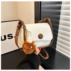 Detail of a vintage contrast crossbody bag with brown pompom charm and fine leather texture
