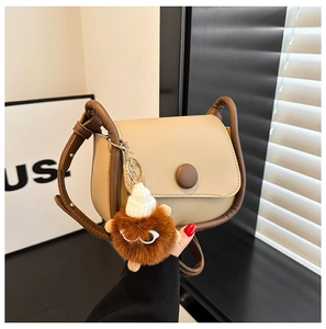 Detail of retro color-block saddle bag with a quirky plush monster bag charm