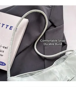 Détail du sac à bandoulière vert menthe avec fines lanières sur costume et livre