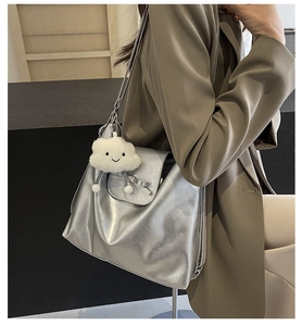 Detalle del bolso tote plateado metalizado con textura de cuero, lazo y colgante de nube