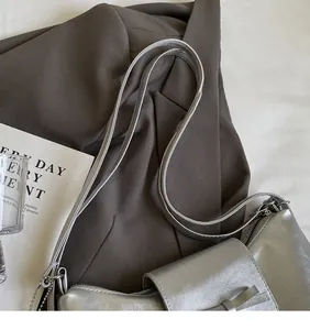 Detail shot of smooth silver shoulder straps and zipper on a metallic tote bag