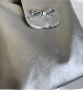 Close-up detail of silver metallic texture and bow design on the flap of the backpack