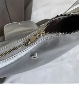 Detail view of the silver tote bag featuring a smooth metal zipper and magnetic snap closure