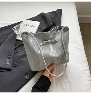 Détail du sac seau argenté à nœud avec texture plissée et fini métallique chic