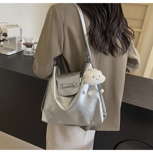 Detail of silver metallic crossbody bag with bow accent and plush cloud charm
