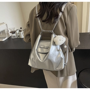 Close-up of silver bow backpack with a white cloud plush charm in a cafe setting