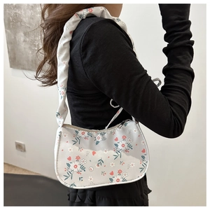Detailed side view of floral canvas underarm bag with pleated cloud strap on model
