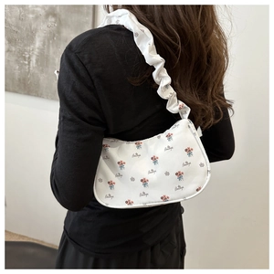 Detail of white half-moon underarm bag featuring floral print and scrunchie shoulder strap