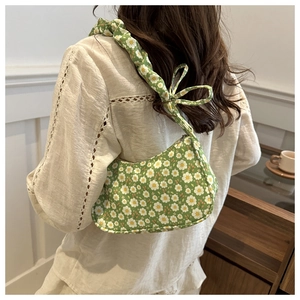 Close-up of green floral underarm bag with decorative bow and ruffled strap