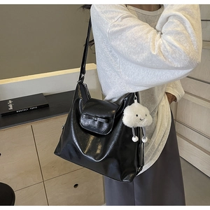 Close-up of black retro shoulder bag featuring a leather bow and plush cloud charm