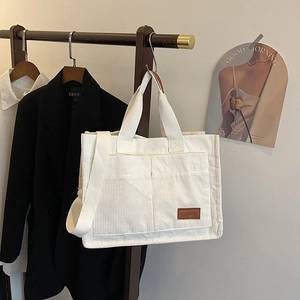 White corduroy tote bag with large dual front pockets and adjustable wide shoulder strap