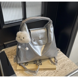 Detail of silver metallic tote bag featuring a cute bow and white plush cloud pendant