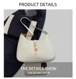 Detailansicht der weißen Halbmond-Tasche mit goldener Schnalle neben einem Smartphone
