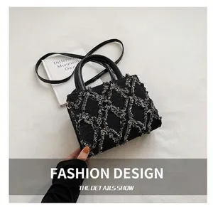 Detail of black tweed crossbody bag with white quilted tassel design and leather handles