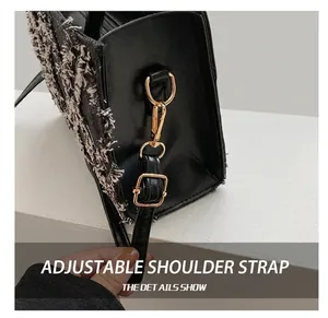 Close-up of golden D-ring and adjustable strap buckle on black tweed handbag