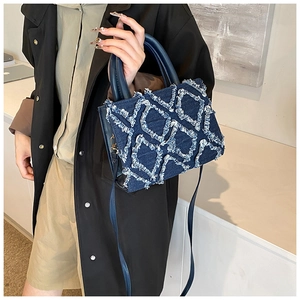 Detail of dark blue denim handbag with diamond quilting and frayed vintage edges
