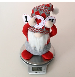 Close-up of Valentine gnome plush holding I Love You sign showing weight on a digital scale
