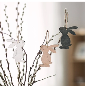Close-up of three wooden Easter bunny ornaments in white, natural wood, and dark grey hanging