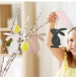Girl hanging minimalist wooden Easter bunny ornaments on willow branches with eggs