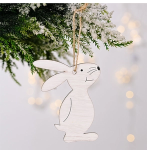 White wooden rabbit pendant hanging on snowy pine branch with warm bokeh background