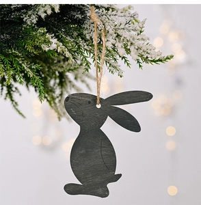 Detail of dark wood bunny pendant hanging from snow-covered branch with rustic hemp rope