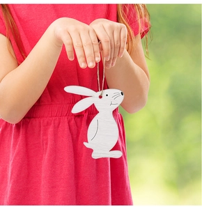 Close-up of white wooden Easter bunny hanging ornament with jute string in child's hand