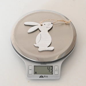 Close-up of lightweight white wooden Easter bunny pendant showing texture and weight