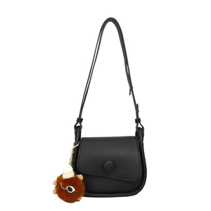 Minimalist black PU leather crossbody bag with cute plush lion pendant on white background