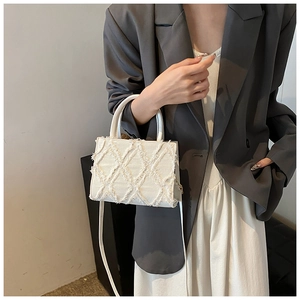 Detail of white quilted handbag with fringe texture and adjustable shoulder strap