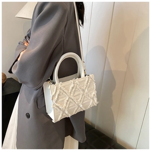 Detailed view of white quilted crossbody bag with textured fringe and sturdy handles