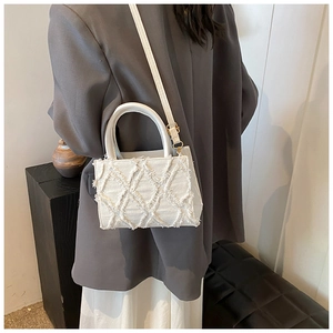 Detail of white canvas crossbody bag with quilted plush texture on a model