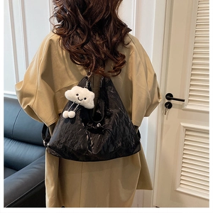 Detailed view of black wrinkled texture shoulder bag with white cloud plush pendant
