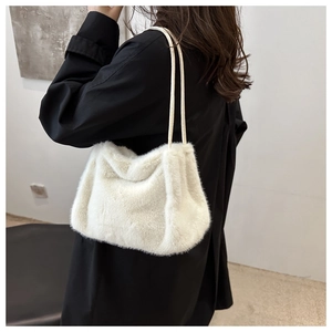 Close-up of fluffy white faux fur tote bag shoulder strap details on a black coat