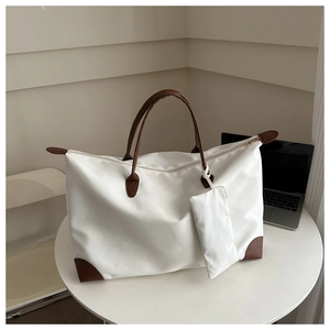 Detailed view of white nylon tote bag with brown leather handles and matching pouch