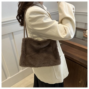 Detail of soft deep brown faux fur texture and slim leather strap on a shoulder bag