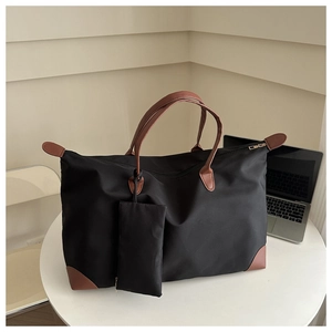 Detail of black nylon tote bag with brown leather handles and matching small pouch