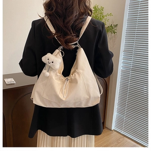 Macro view of cream drawstring tote bag featuring soft leather texture and cloud charm