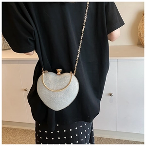 Detailed view of a silver heart-shaped evening bag with glitter surface and metal chain
