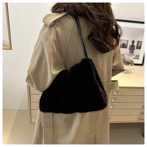 Detail of black faux fur shoulder bag worn with a beige trench coat in an elegant room